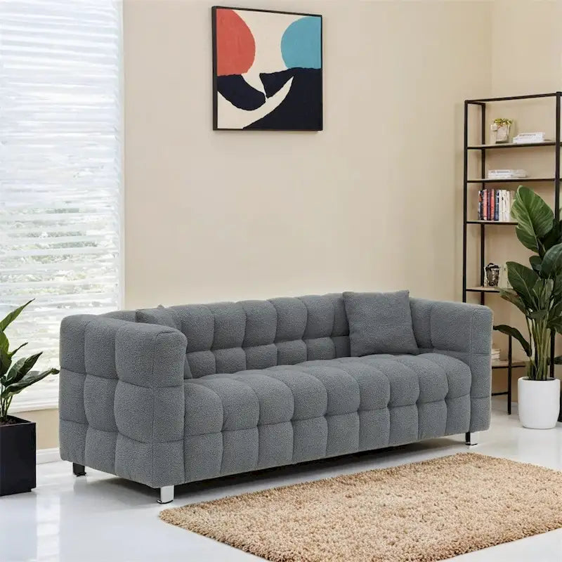 Canapé en polaire Teddy avec deux coussins décoratifs et repose-pieds en métal.